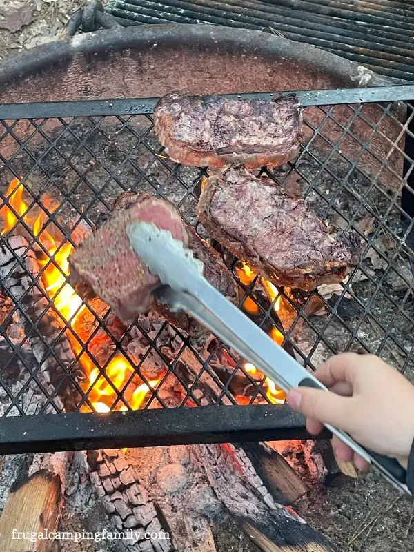 cooking steaks over a campfire